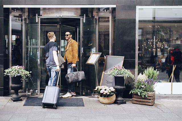 To mænd som står ude foran et hotel.